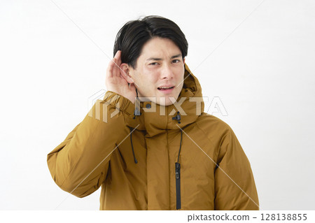 A man wearing a down jacket listening with his hand on his ear, white background A man wearing a down jacket listening with his hand on his ear, white background 128138855