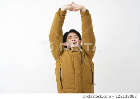 Man wearing down jacket stretching white background Man wearing down jacket stretching white background 128138868