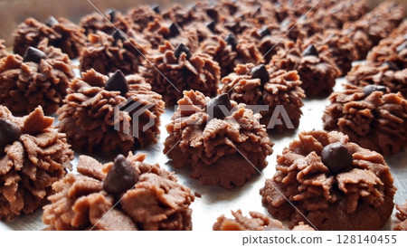 Delicate and crispy chocolate kue semprit with a rich cocoa flavor, beautifully shaped with a swirl pattern. A classic Indonesian cookie perfect for snacking or festive celebrations. 128140455