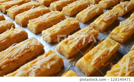 Buttery and savory kastengel cookies topped with grated cheese, offering a rich, crumbly texture and cheesy flavor. A classic Indonesian treat perfect for celebrations or snacking. 128140471