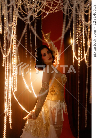 Young woman in vintage corset costume posing under chandelier on dark background Young woman in vintage corset costume posing under chandelier on dark background 128140518