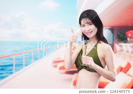 Young woman wearing swimsuit drinking sparkling wine on cruise ship Young woman wearing swimsuit drinking sparkling wine on cruise ship 128140573