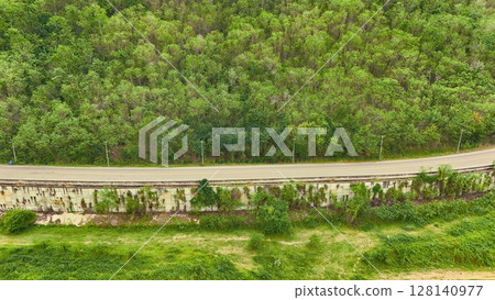 Aerial view of a road in the middle of the forest. Top view of asphalt road through forest with car adventure. Healthy environment road trip travel. Aerial view of a road in the middle of the forest. Top view of asphalt road through forest with car adventure. Healthy environment road trip travel. 128140977