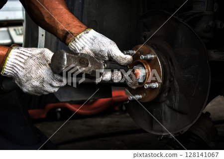 Car drive shaft repair by auto mechanic. removing the nuts of the car drive shaft Car drive shaft repair by auto mechanic. removing the nuts of the car drive shaft 128141067