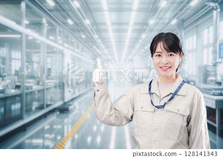 Smiling young woman working in a large factory 128141343
