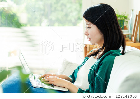 Young woman using a computer in the living room Young woman using a computer in the living room 128142016