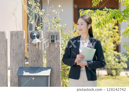 A woman in a suit standing in front of a house 128142742