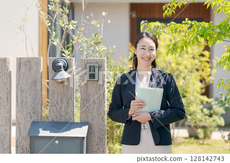 A woman in a suit standing in front of a house 128142743