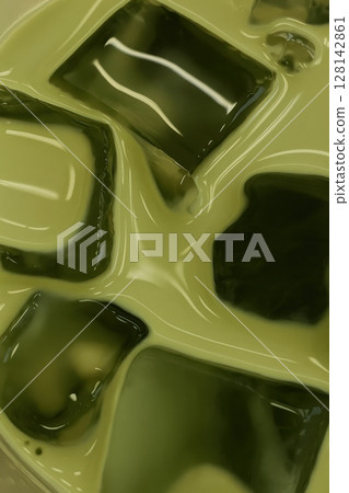 Close-up of iced matcha latte with glossy green ice cubes floating in creamy tea 128142861