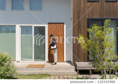 A woman in a suit closing the front door 128142966