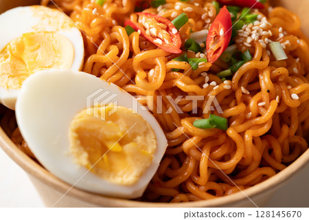 Spicy Korean dried instant noodles with boiled egg, sliced scallions, sesame seed and fresh chili  128145670