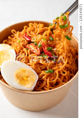 Spicy Korean dried instant noodles with boiled egg, sliced scallions, sesame seed and fresh chili  128145671