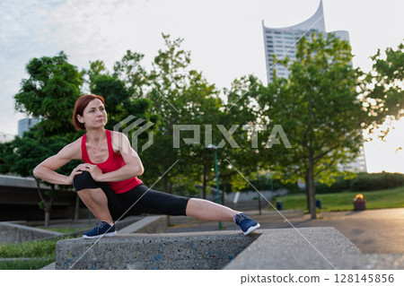 Woman working out in the city, doing bodyweight strength exercises outdoors 128145856
