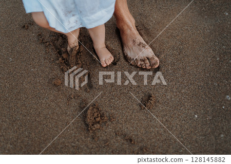 Legs and feet of family standing on beach on summer holiday, a midsection. Legs and feet of family standing on beach on summer holiday, a midsection. 128145882