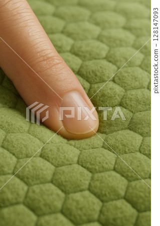 Finger presses soft green hexagon textured fabric 128147093