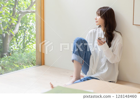 A woman sitting on the floor and using a smartphone 128148460