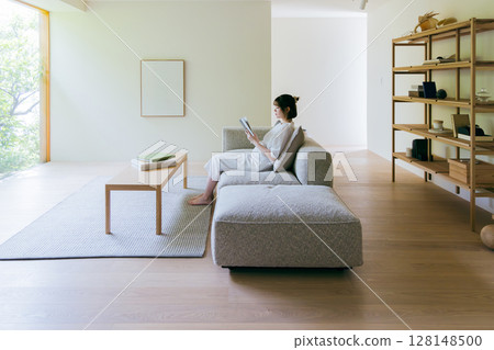 A woman reading a book in the living room 128148500