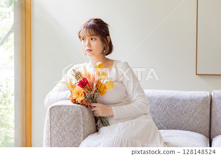 Woman holding a bouquet in the living room 128148524