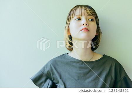 Half-Japanese woman leaning against a wall 128148861
