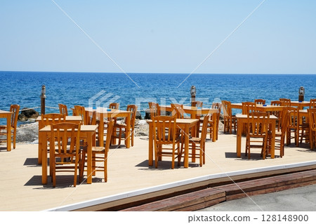 Empty Oceanfront Restaurant Seating with Wooden Tables 128148900