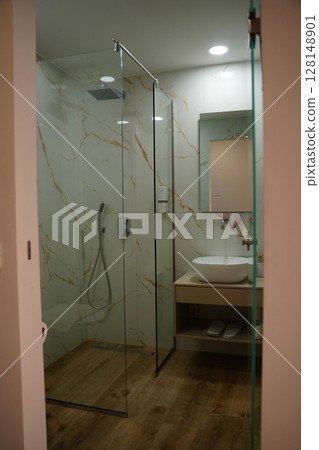 Modern Bathroom with Glass Shower and Marble Walls 128148901