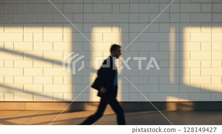 blurred male silhouette over white brick wall and under sunlight blurred male silhouette over white brick wall and under sunlight 128149427