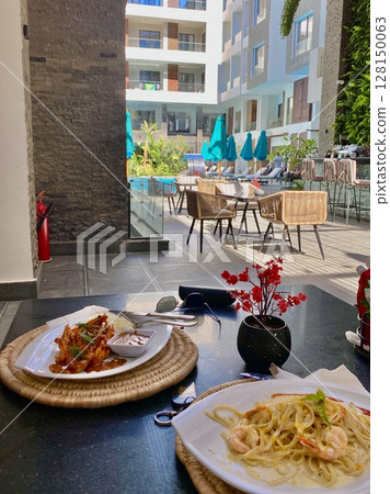 lunch on the terrace in an apartment overlooking the relaxation area and pool, summer holidays lunch on the terrace in an apartment overlooking the relaxation area and pool, summer holidays 128150063