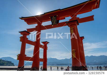 Close-up view of the famous Itsukushima shrine red torii gate and people walking on the beach in Miyajima, Japan 128150574