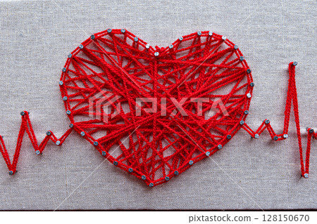 Red heart and heartbeat lines string art made with tangled red yarn on metal nails at canvas texture Red heart and heartbeat lines string art made with tangled red yarn on metal nails at canvas texture 128150670