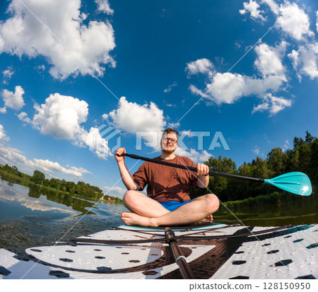 Man Taking Selfie on Paddleboard in Scenic Lake 128150950