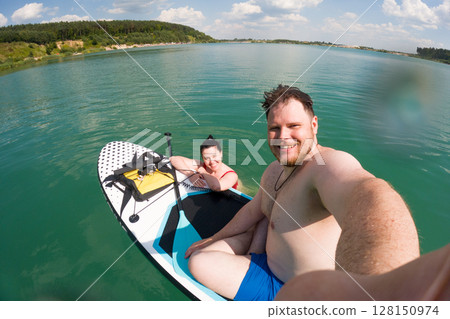 Couple Paddleboarding on a Sunny Lake 128150974