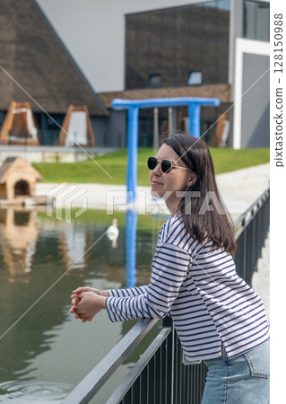 Woman Relaxing by Pond with Modern Architecture 128150988