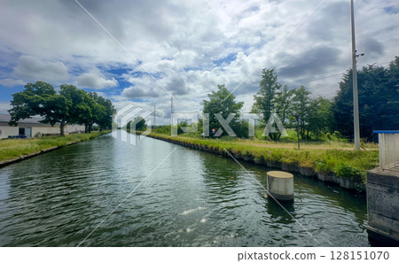 A Serene and Picturesque Canal View Beneath a Beautifully Cloudy Sky that Inspires Calmness A Serene and Picturesque Canal View Beneath a Beautifully Cloudy Sky that Inspires Calmness 128151070