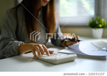 Sn accountant calculating and reviewing printed financial charts and data sheets 128151137