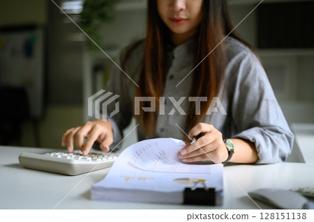 Sn accountant calculating and reviewing printed financial charts and data sheets 128151138