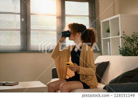 Young woman sipping from a mug and using smartphone in a stylish home interior Young woman sipping from a mug and using smartphone in a stylish home interior 128151149