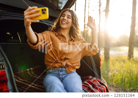Happy Woman is resting in trunk of car and taking selfie. Selfie time. Lifestyle, travel Happy Woman is resting in trunk of car and taking selfie. Selfie time. Lifestyle, travel 128151164