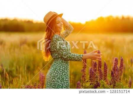 Stylish woman in a straw hat with a bouquet of flowers on a field with lupins. Lifestyle concept. Stylish woman in a straw hat with a bouquet of flowers on a field with lupins. Lifestyle concept. 128151714