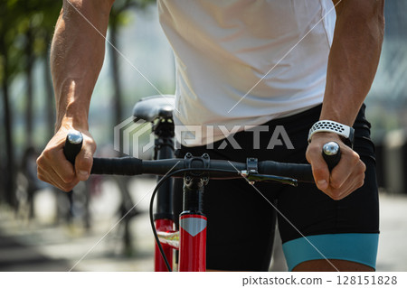 Close up of cyclist's hands holding handlebars of red bike during an outdoor ride. 128151828