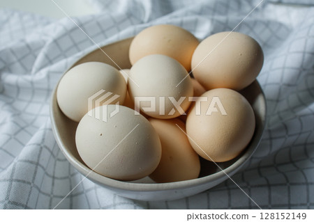 Fresh farm chicken eggs in bowl on kitchen towel close up Fresh farm chicken eggs in bowl on kitchen towel close up 128152149