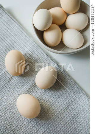 Fresh farm chicken eggs in a bowl and on a kitchen grey towel 128152154