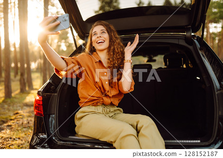 A woman in the trunk of a car at sunset. Traveling by car, camping. Active lifestyle. A woman in the trunk of a car at sunset. Traveling by car, camping. Active lifestyle. 128152187