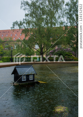 Small house for ducks in the big fountain lake in the park in Copenhagen city. A small bird wooden miniature house for nesting and protecting. Eco and animal friendly decision for safe birds life. 128152922