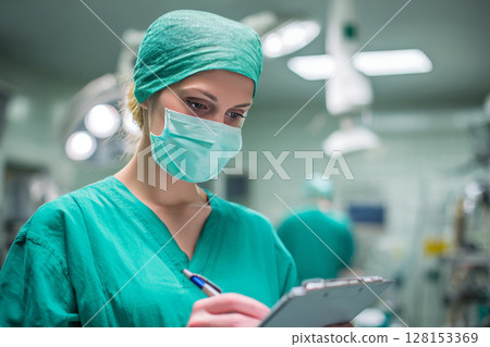 Focused Surgeon Writing Notes in Operating Room Environment. 128153369