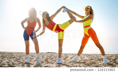 Dancing on beach. Woman in colorful swimsuits are dancing in morning. ?oncept of fitness, aerobics. 128153965