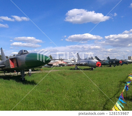 A Stunning Display of Military Jets Parked in an Open Green Field Under a Bright Blue Sky A Stunning Display of Military Jets Parked in an Open Green Field Under a Bright Blue Sky 128153987
