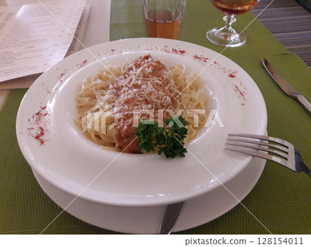 A Plate of Pasta Topped with Sauce, Grated Cheese, and Parsley, Served with Drinks A Plate of Pasta Topped with Sauce, Grated Cheese, and Parsley, Served with Drinks 128154011