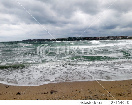 A rugged coastal landscape with rocky outcrops and crashing waves under a gloomy, cloud-covered sky, featuring a staircase and small structure A rugged coastal landscape with rocky outcrops and crashing waves under a gloomy, cloud-covered sky, featuring a staircase and small structure 128154028