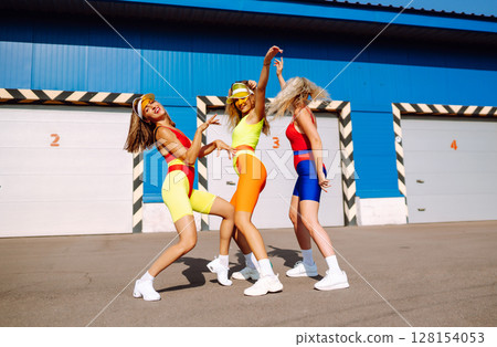 Dancing on beach. Woman in colorful swimsuits are dancing in morning. ?oncept of fitness, aerobics. 128154053