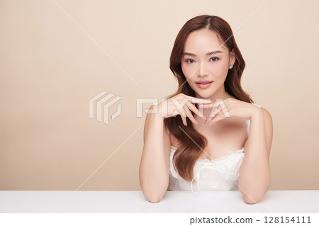 A beautiful young Asian woman with clean, fresh skin against a beige background. Skincare, facial treatment, cosmetology, beauty, and spa. An elegant portrait of an Asian woman. A beautiful young Asian woman with clean, fresh skin against a beige background. Skincare, facial treatment, cosmetology, beauty, and spa. An elegant portrait of an Asian woman. 128154111